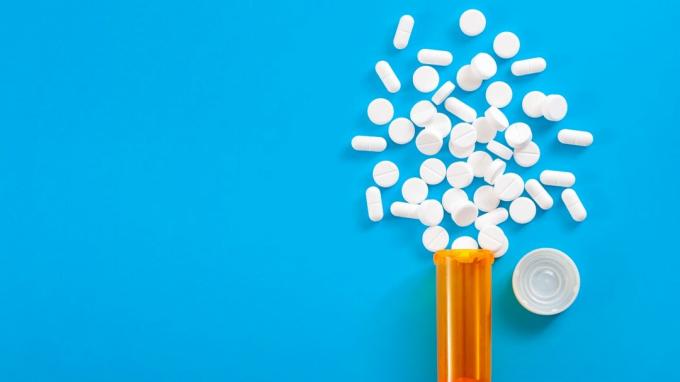 Konsep obat-obatan, penghilang rasa sakit opioid dan resep obat-obatan dengan tampilan atas botol resep oranye dari pil oxycodone dan hydrocodone tumpah di latar belakang biru dengan ruang salinan